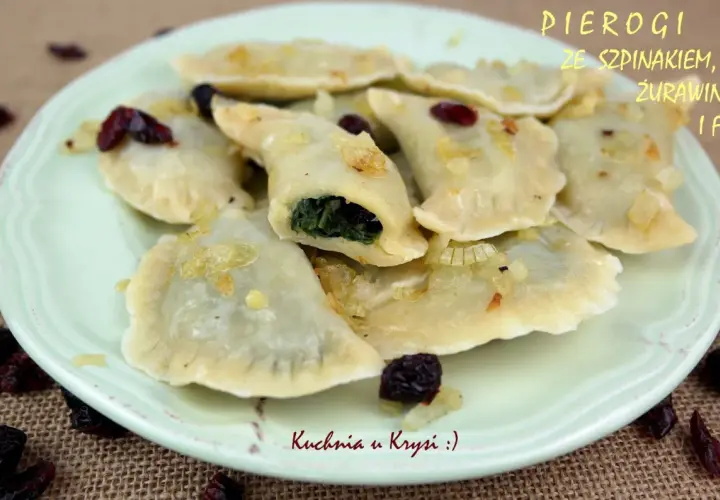 Pyszne pierogi ze szpinakiem i serem feta, okraszone cebulką i żurawiną, na talerzu.