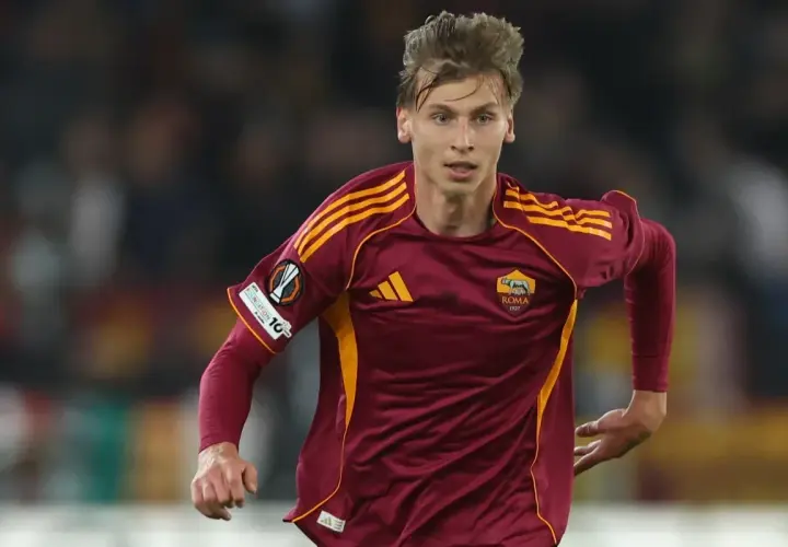 Piłkarz AS Roma w bordowej koszulce z żółtymi pasami, gotowy do gry przeciwko Genoa CFC.