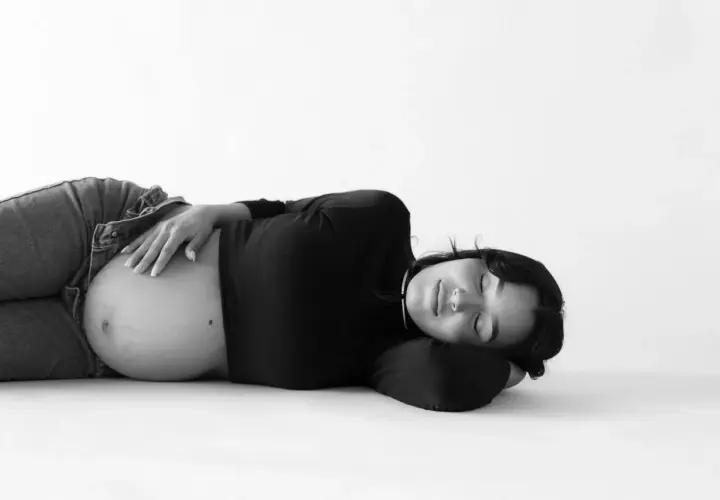 Donna incinta dorme serena, con la mano sul pancione. La vena cava è compressa, ma la serenità della gravidanza prevale.