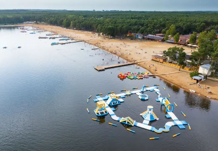 Sielpia atrakcje: dmuchany plac zabaw na wodzie, plaża z ludźmi, wypożyczalnia sprzętu wodnego i las.