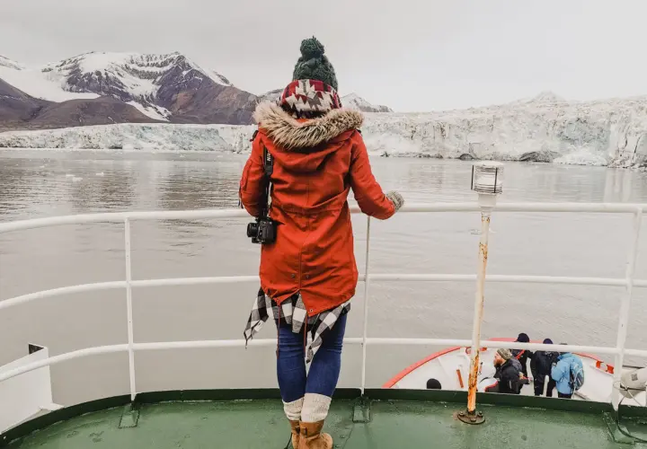 Podróżniczka podziwia lodowce na archipelagu Svalbard. W oddali widać góry i morze.