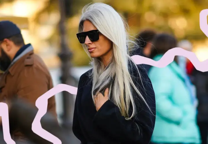Mujer con pelo blanco largo y liso, gafas de sol oscuras y abrigo negro. La moda pelo blanco mujer es tendencia.