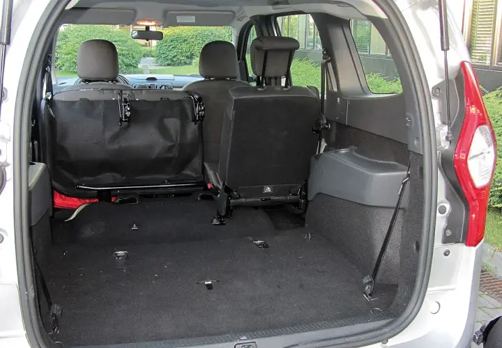 Pusta przestrzeń bagażnika Dacia Lodgy, gotowa na podróż. Widoczne złożone tylne siedzenia i siatka zabezpieczająca.
