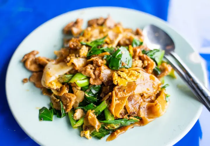 En tallrik med pad see ew, en klassisk thailändsk nudelrätt med breda risnudlar, ägg, grönsaker och kött.