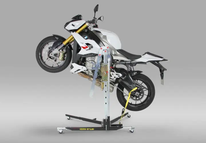 Biały motocykl BMW uniesiony na podnośniku motocyklowym centralnym.