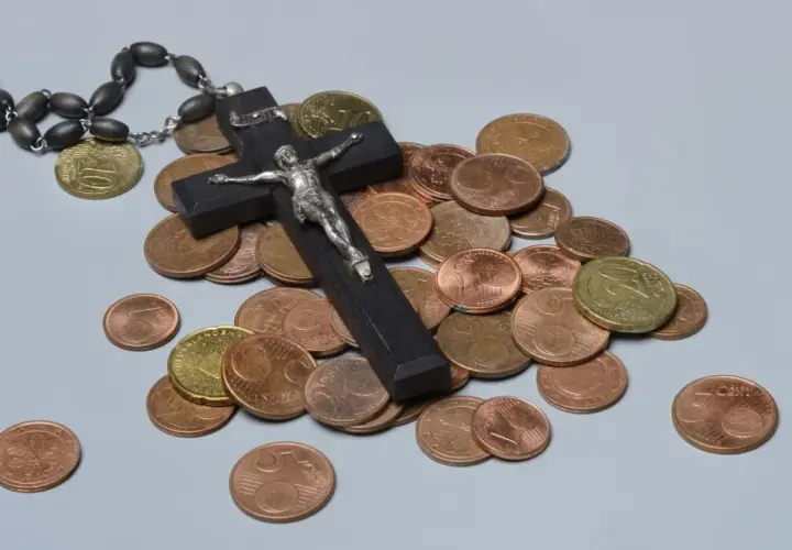 Holzkreuz mit Korpus, Rosenkranz und Münzen. Ein Symbol für das Kirchgeld in Bayern.