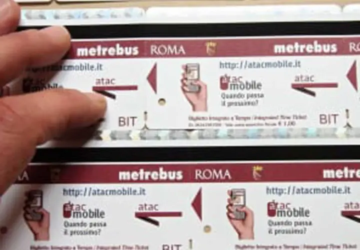 Dita sfiorano un biglietto metro Roma da 2 euro, con logo Atac e indicazioni per l'acquisto online.