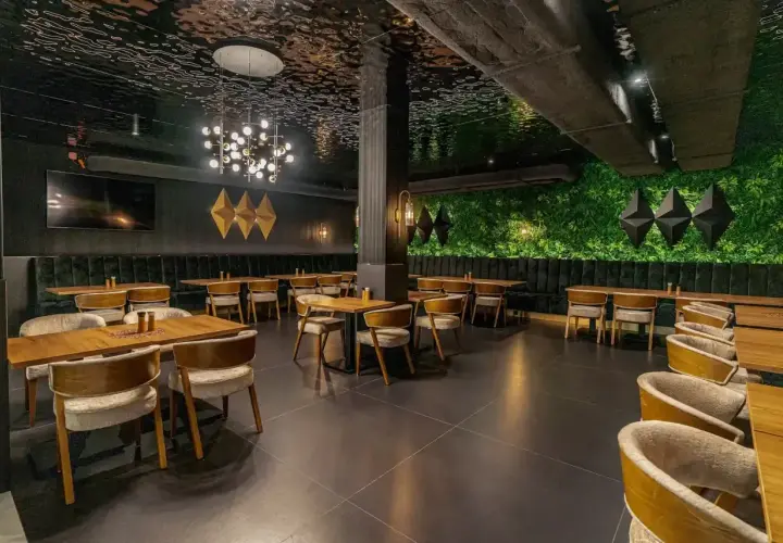 Elegancka restauracja z zieloną ścianą i nowoczesnym sufitem. Idealne miejsce na wykwintne białowieża jedzenie.