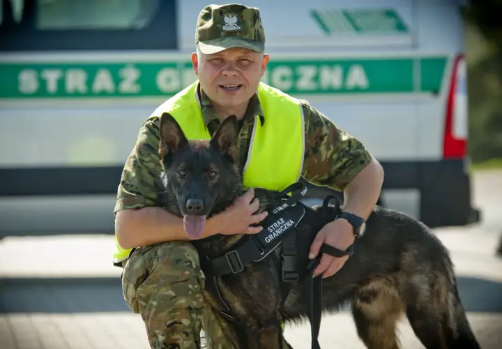 Funkcjonariusz Straży Granicznej z psem, który pomaga w pracy. Psy pracujące to wierni towarzysze na służbie.