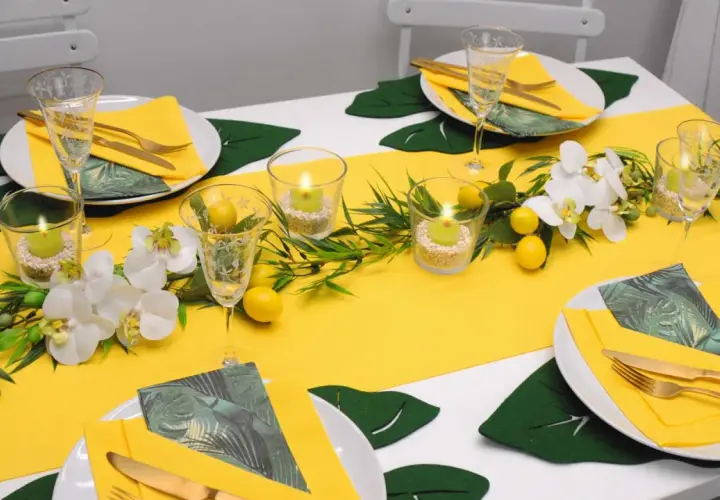 Eine sommerliche Tafel mit gelbem Läufer, Orchideen, Zitronen und Kerzen. Perfekt für schnelle Tischdeko Sommer.