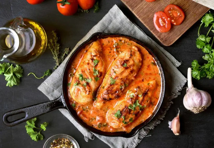 Poitrines de poulet en sauce crémeuse à la tomate, parsemées de persil. Un plat savoureux qui rappelle le poulet chorizo.