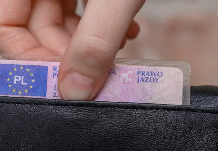 Dłoń wkłada prawo jazdy do portfela. Wkrótce czekają Cię badania lekarskie na prawo jazdy Poznań.