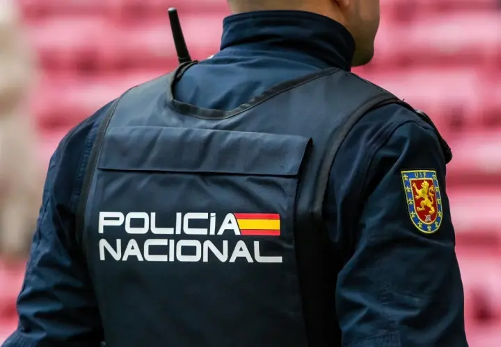 Policjant w kamizelce z napisem "POLICIA NACIONAL" i flagą Hiszpanii. Służba w policji Hiszpanii to odpowiedzialność.