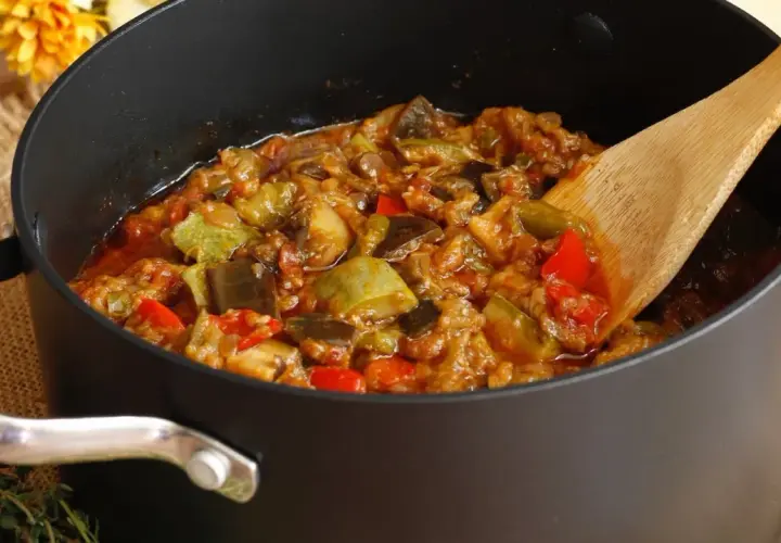 Une poêle remplie de ratatouille, comme dans le film, avec des légumes colorés et une cuillère en bois.