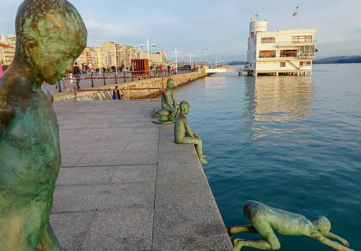 Los raqueros, esculturas de bronce, observan el mar desde el paseo marítimo. Uno se lanza al agua, otro espera sentado.