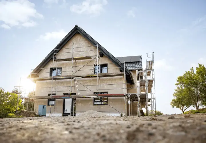 Maison en construction avec échafaudages. Le chantier laisse imaginer le futur prix de rénovation maison.