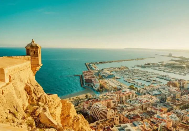 Vista panorámica de Alicante, con su castillo, el puerto deportivo lleno de barcos y el mar azul. Así es cual es la costa blanca.