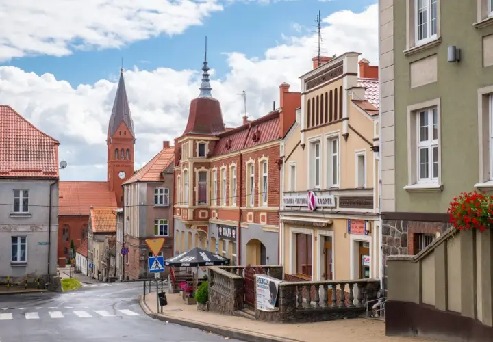 Ulica w gminie Skarszewy z kościołem w tle i kolorowymi kamienicami.