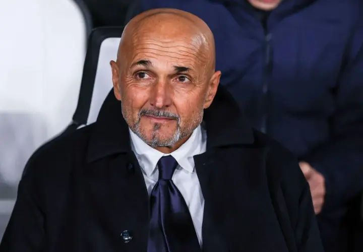 Łysy mężczyzna z brodą, ubrany w białą koszulę i granatowy krawat, w ciemnym płaszczu. To trener Juventusu, wpatrzony w dal.