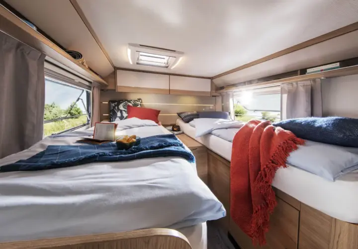 Deux lits jumeaux confortables, aménagés comme un lit à la française, invitent au repos dans ce camping-car lumineux.