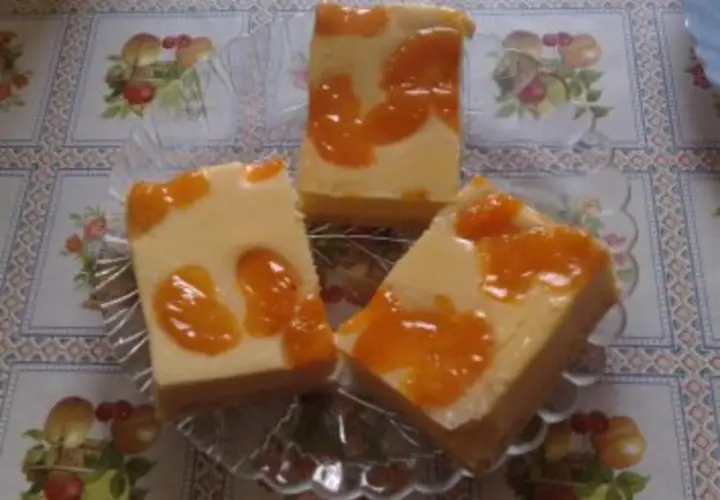Drei Stücke faule weiber kuchen mit Mandarinen auf einem Tisch mit Blumenmuster.