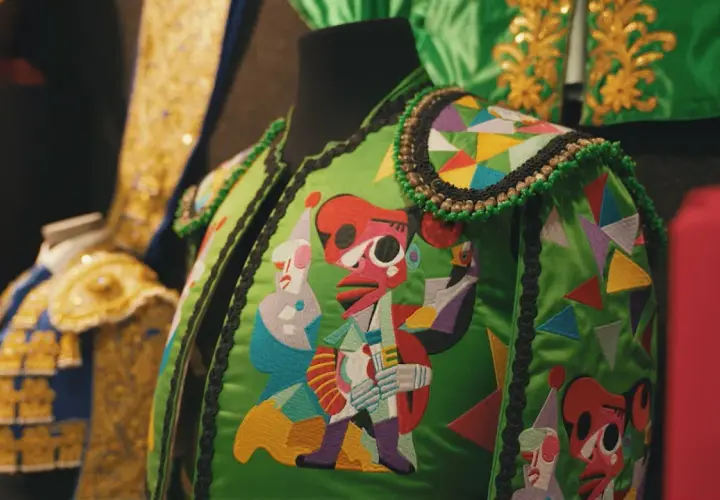 Detalle de coloridos bordados en partes del traje de torero, con figuras abstractas y geométricas sobre fondo verde.