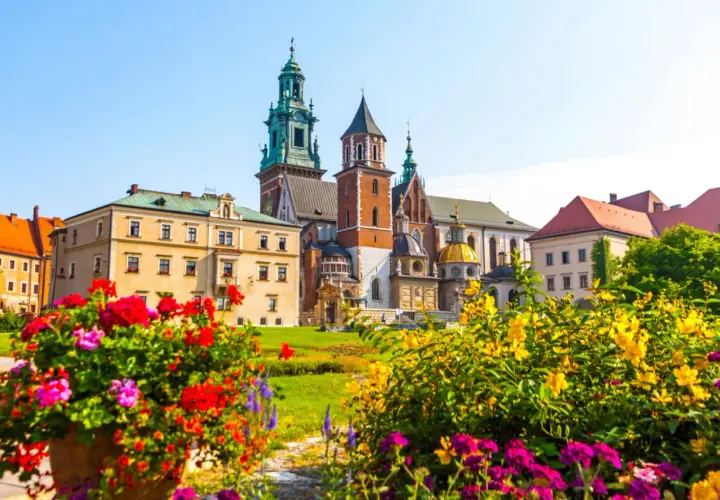 Krakowski Wawel, wpisany na **UNESCO listę polską**, w otoczeniu kwitnących kwiatów.