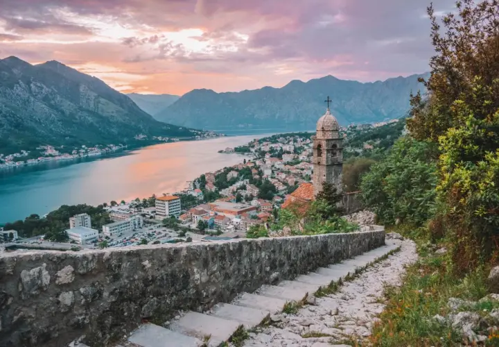 Escaleras de piedra con vistas a la bahía de Kotor al atardecer. Un lugar ideal donde viajar en julio barato.