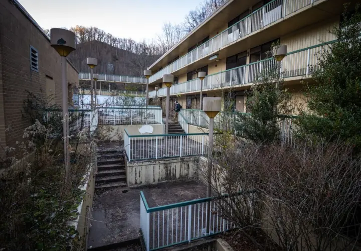 Opuszczone miasta w Polsce: zaniedbany hotel z widokiem na wzgórza, zarośnięte schody i zniszczone balustrady.