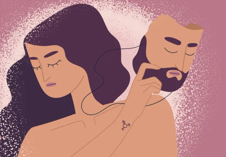 Una persona con lunghi capelli scuri si toglie una maschera da uomo barbuto, simboleggiando la transizione di genere.