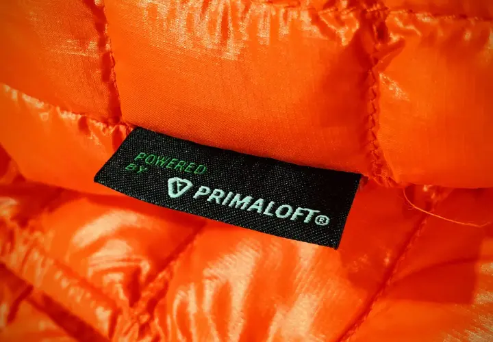 Pomarańczowa, pikowana tkanina z wszywką "Powered by Primaloft®". To materiał izolacyjny, który zapewnia ciepło.