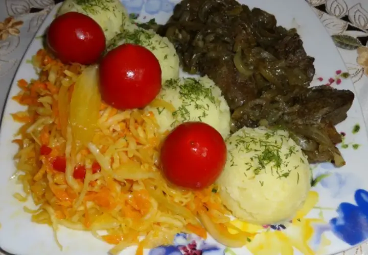 Talerz z wątróbką drobiową, ziemniakami, surówką z kapusty i marchewki oraz pomidorkami koktajlowymi.