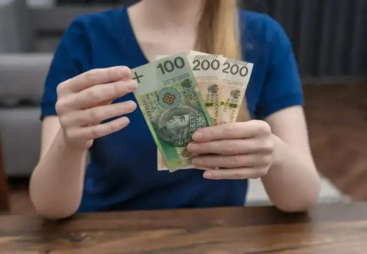 Dłonie trzymają banknoty: 100 zł i dwa 200 zł. To polskie "kosiniakowe" na drobne wydatki.