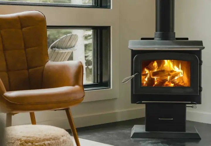 Un confortable fauteuil en cuir brun fait face à un poêle à bois non étanche, où des flammes dansent joyeusement dans le foyer.