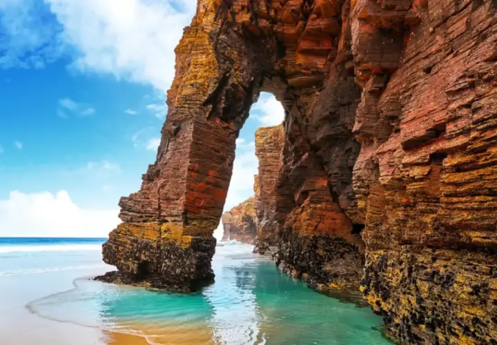 Arco natural en la playa de las Catedrales, un lugar ideal donde viajar en agosto en España.