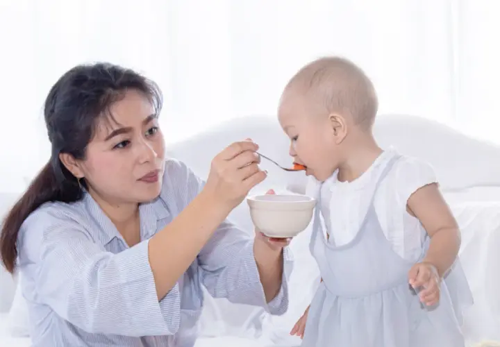 Madre alimenta a su bebé con cuchara. Mi bebé come bien pero no engorda, aunque se ve feliz y saludable.
