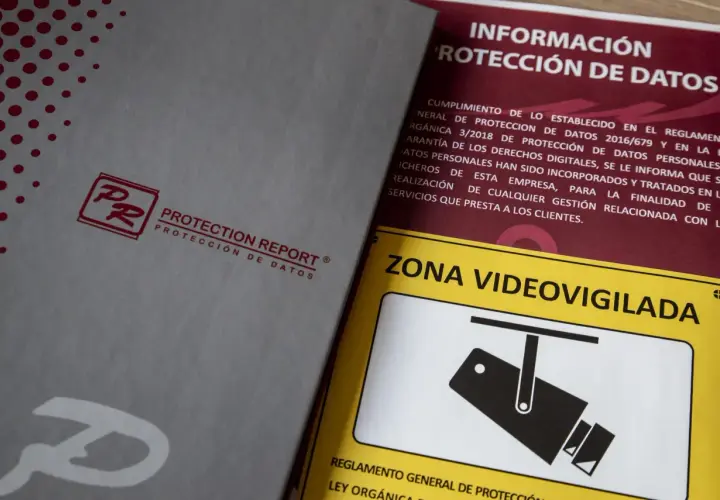 Documentos sobre protección de datos y un cartel de "Zona Videovigilada", parte de una feria de seguridad.