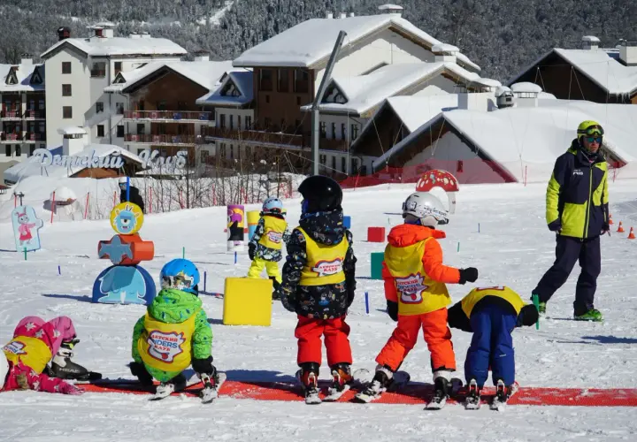 Dzieci na stoku, gotowe na ferie 2026. Wesołe kolorowe stroje narciarskie i śnieg wokół.