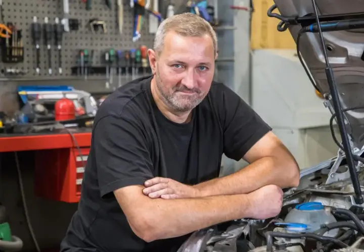 Mechanik przy otwartej masce Passata B6, który nie odpala i nie kręci.
