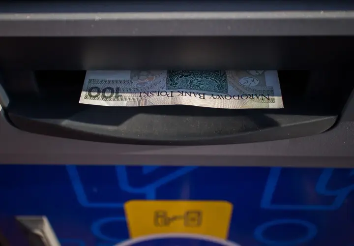 Sto złotych w banknocie wychodzi z bankomatu. To mój etatowy dochód, który właśnie wypłaciłem.