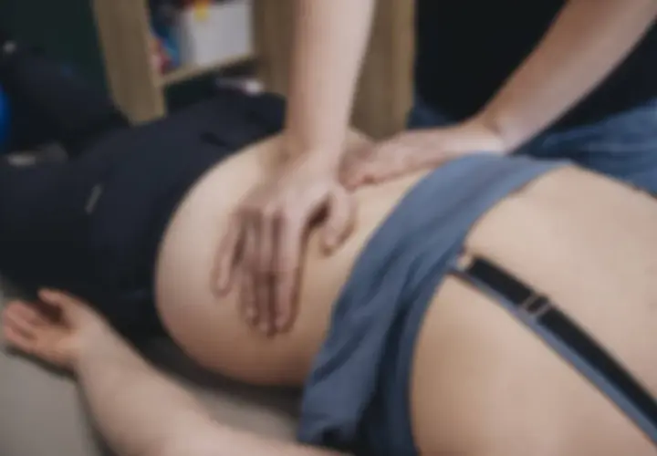 Fizjoterapeuta masuje biodro pacjentki, pomagając rozluźnić napięty mięsień gruszkowaty. Ćwiczenia i terapia mogą przynieść ulgę.