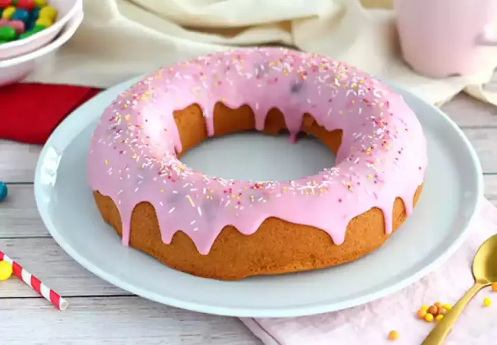 En stor donut tårta med rosa glasyr och strössel. Perfekt för ett kalas!