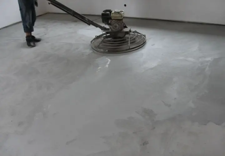 Pracownik poleruje betonową posadzkę maszyną. Powierzchnia jest gładka i lśniąca, tworząc nowoczesny wygląd.