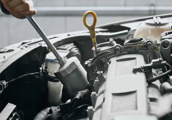 Mechanik sprawdza poziom oleju, co może być jednym z objawów uszkodzonej pompy oleju.