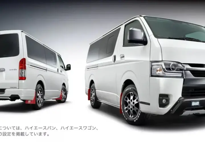 Dwa białe vany Toyota Hiace z pakietem GR Parts, jeden z tyłu, drugi z przodu, z czerwonymi błotnikami.