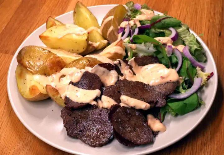 En tallrik med ugnsrostad potatis, saftig kebab och en fräsch sallad med rödlök. En perfekt kebab på plåt för en härlig middag.