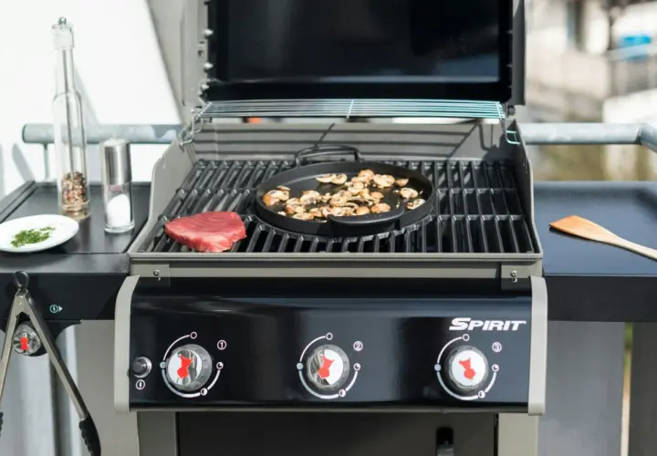 En portabel gasolgrill bäst i test förbereds med en rå biff och champinjoner. Kryddkvarn och saltkaret står redo.