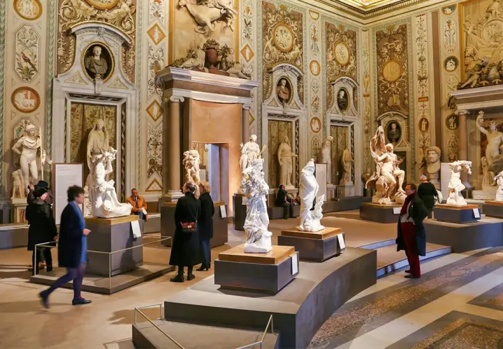 Salle ornée de sculptures classiques à la Villa Borghese. Des visiteurs admirent des œuvres d'art dans un décor somptueux.