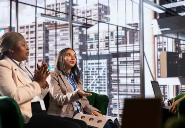Two women in a meeting discuss business strategy, perhaps inspired by their organizational management degree.