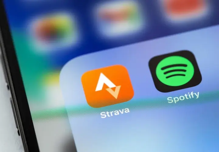 Ikona aplikacji Strava, idealna do śledzenia tras rowerowych, obok Spotify na ekranie smartfona.
